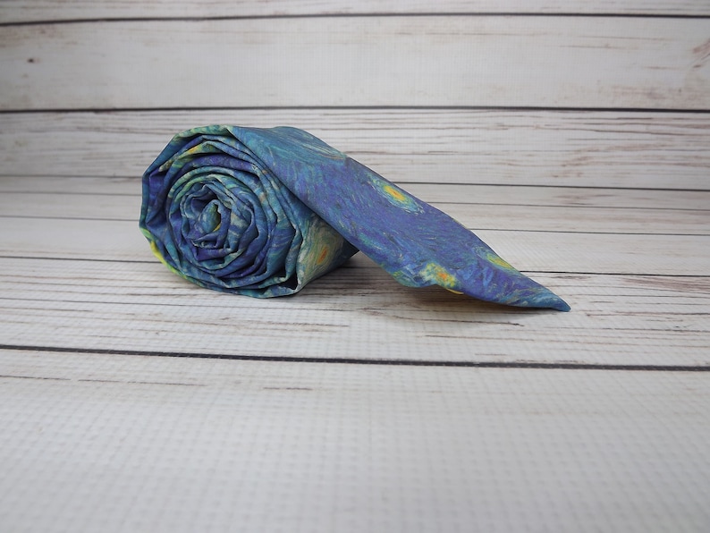 May include: A blue and yellow patterned tie rolled up on a white wooden surface.