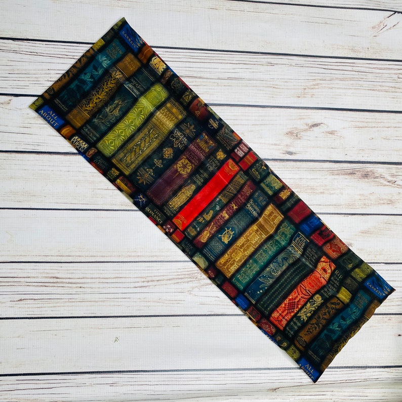 May include: A fabric panel with a pattern of vintage book spines. The spines are arranged in rows and feature a variety of colors, including red, blue, green, and gold. The fabric is perfect for crafting projects, such as tote bags, pillows, and quilts.