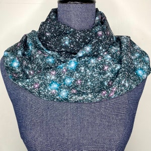 May include: A black infinity scarf with a galaxy print featuring white, blue, and pink stars.