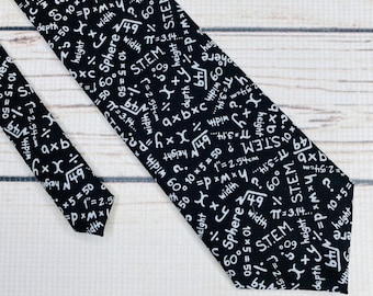 Puede incluir: Una corbata negra con un patrón blanco de ecuaciones y fórmulas matemáticas. La corbata presenta varios símbolos, números y palabras como 'Sphere', 'STEM' y 'altura'.