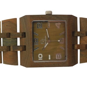 Puede incluir: Un reloj de pulsera de madera marr&oacute;n con una esfera cuadrada y una correa de madera marr&oacute;n. La esfera del reloj tiene marcadores de hora con n&uacute;meros romanos y un fondo marr&oacute;n.