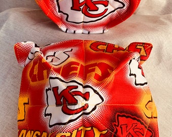May include: Two red, white, and yellow fabric bowl cozies with the Kansas City Chiefs logo. The cozies are quilted and have a yellow stitching detail.