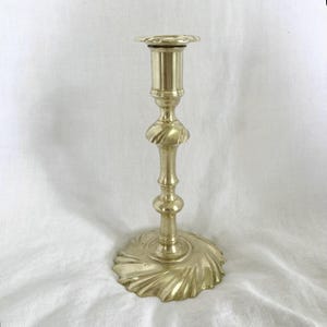 Puede incluir: Un candelero de latón con una base estriada y un diseño decorativo en espiral. El candelero tiene un tallo alto y delgado y una parte superior circular para sostener una vela. El diseño es vintage y elegante.