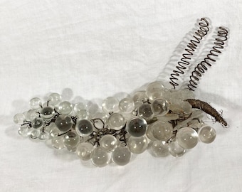 May include: A cluster of clear glass grapes with a brown wire stem and two coiled wire vines.