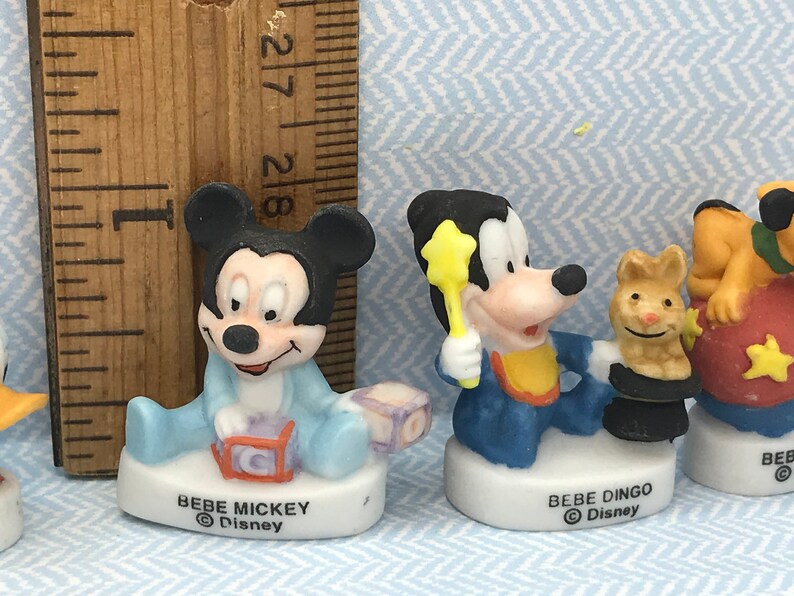 Może przedstawiać: Zestaw czterech porcelanowych figurek postaci z Disneya, w tym Myszki Miki, Goofy'ego, Kaczora Donalda i Pluto. Każda figurka ma około 5 cm wysokości i przedstawia motyw dziecięcy. Figurki są pomalowane żywymi kolorami i mają błyszczące wykończenie.