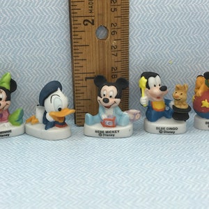 Może przedstawiać: Zestaw pięciu porcelanowych figurek postaci z Disneya, w tym Myszki Miki, Minnie Mouse, Kaczora Donalda, Goofy'ego i Pluto. Każda figurka ma około 5 cm wysokości i przedstawia postać w stylu dziecięcym. Figurki mają r&oacute;żne stroje i wyrażenia twarzy.