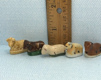 May include: Five miniature ceramic figurines of farm animals. The animals are a brown and white cow, a brown cow, a white sheep, a brown and white cow, and a brown cow. The figurines are about 1 inch tall and are arranged in a row.