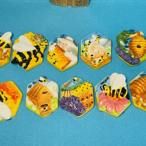 May include: Ten colorful hexagonal ceramic tiles with bee and honeycomb designs. Each tile features a different bee-themed scene, including bees, honeycombs, flowers, and a beehive. The tiles are perfect for adding a touch of whimsy to any space.