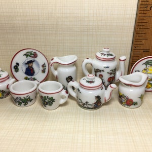 May include: A miniature porcelain tea set with a red and white floral design. The set includes a teapot, creamer, sugar bowl, two cups, and a plate.