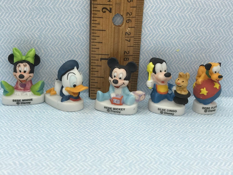 Może przedstawiać: Zestaw sześciu małych ceramicznych figurek postaci z Disneya, w tym Myszki Miki, Minnie Mouse, Kaczora Donalda, Goofy'ego, Pluto i małego kota. Każda figurka ma około 5 cm wysokości i przedstawia inną pozę i czynność. Figurki są pomalowane w jaskrawych kolorach i mają błyszczące wykończenie.