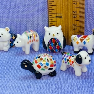 May include: Six small ceramic figurines of various animals, including a bear, a cow, a turtle, a dog, an owl, and a polar bear. Each figurine is painted with a colorful geometric pattern.