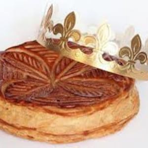 May include: A traditional French King Cake with a golden crown on top. The cake is decorated with a leaf pattern and is a popular treat for Epiphany.