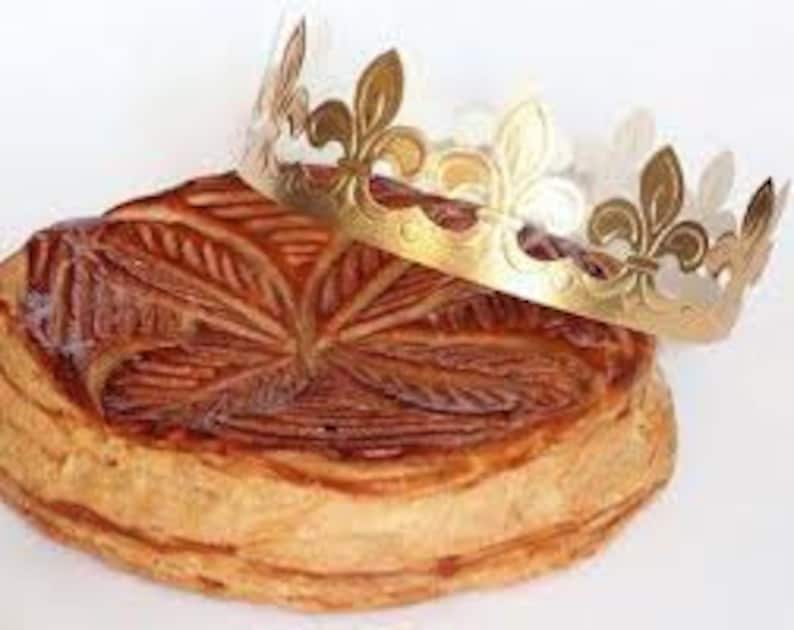 May include: A traditional French King Cake with a golden crown on top. The cake is decorated with a leaf pattern and is a popular treat for Epiphany.