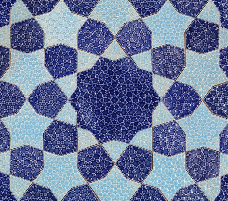 May include: Close-up of a repeating pattern of blue and light blue star-shaped tiles. The tiles have a textured surface with a mosaic-like design. The pattern creates a symmetrical and visually appealing design, suitable for home decor.