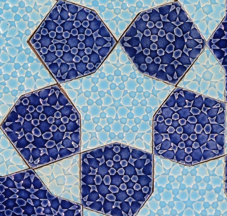 May include: Close-up of a decorative tile pattern featuring geometric shapes in shades of blue and light blue. The design includes octagonal tiles with intricate star and floral patterns, creating a visually appealing mosaic.