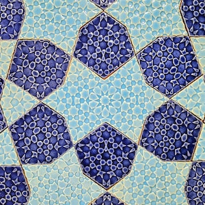 May include: Close-up of a geometric tile pattern in shades of blue and light blue. The design features octagonal shapes with intricate star and dot patterns, creating a mosaic effect. The tiles have a textured, glazed appearance.