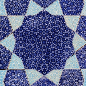 May include: Close-up of a mosaic tile pattern featuring a central eight-pointed star in deep blue, surrounded by lighter blue and turquoise star shapes. The intricate design is composed of small, geometric shapes.