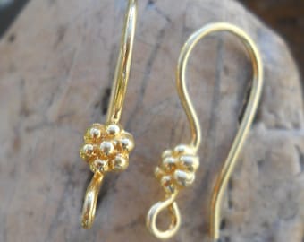 May include: A pair of gold-toned earring hooks with a textured flower design at the top.