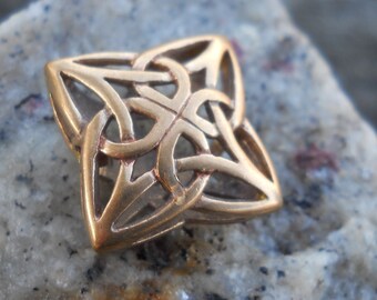 May include: A gold-colored metal Celtic knot pendant with a square shape and intricate woven design.
