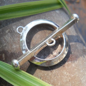May include: Silver toggle clasp with a round, smooth ring and a straight bar. The clasp is designed for jewelry making.
