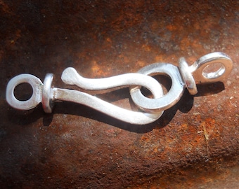 May include: Silver clasp with a loop on one end and a hook on the other. The clasp is designed to be used for jewelry or other crafts.