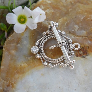May include: Silver toggle clasp with a decorative rope design and a clear rhinestone. The clasp is designed for jewelry making.