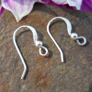 May include: Two silver earring hooks with a small ball at the end of each hook.