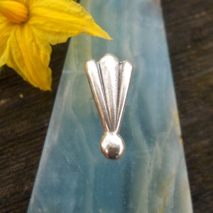 Può includere: Un ciondolo in metallo color argento con un design a forma di ventaglio e una palla rotonda nella parte inferiore.