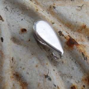 May include: A silver teardrop-shaped pendant with a hook closure.
