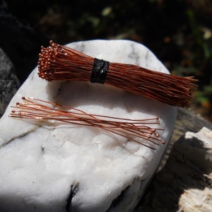 May include: A bundle of copper wire with small, round beads at the end of each wire. The wire is wrapped together with a black rubber band.