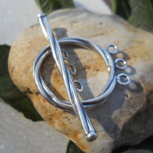 May include: Silver toggle clasp with a twisted bar and three loops. The clasp is designed for jewelry making.
