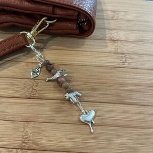 May include: A white ceramic mug with a black handle and the text "But First, Coffee" in a bold, black font. The mug is set against a blurred background, suggesting a cozy setting.