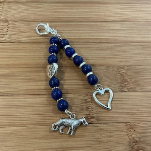 May include: A blue beaded keychain with a silver paw print charm, a silver heart charm, and a silver dog charm.