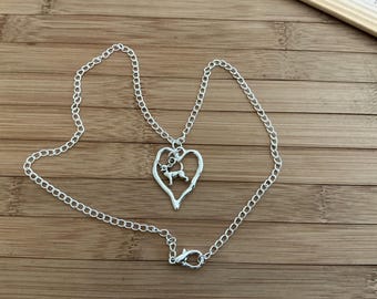 May include: A silver chain necklace with a heart-shaped pendant featuring a small dog silhouette.