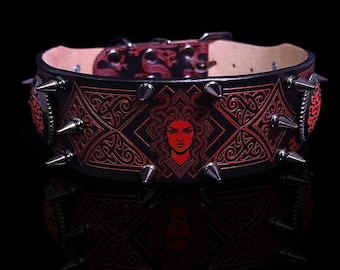 May include: Black leather dog collar with red Medusa graphic and Celtic knotwork. The collar features silver-colored spikes and a buckle closure. The design is reflected in the glossy black surface below.