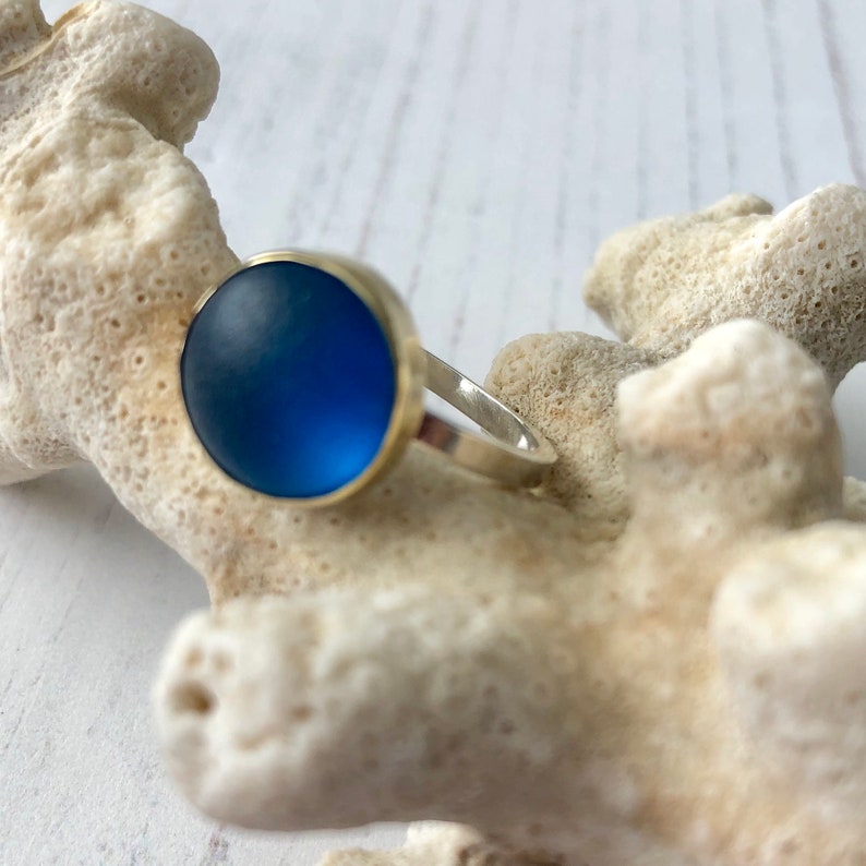 May include: A silver ring with a round, blue glass stone.