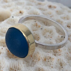 May include: A silver ring with a gold band and a blue glass stone.