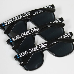 May include: Three pairs of black sunglasses with dark lenses. Each pair has a white anchor and the text "Ron's Cruise Crew" on the arms.