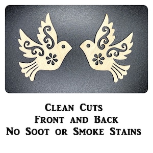 Op de afbeelding: Twee houten duiven met ingewikkelde ontwerpen, uitgesneden uit hout. De duiven kijken elkaar aan en hebben een bloemdessin in het midden van hun borst. De tekst "CLEAN CUTS FRONT AND BACK NO SOOT OR SMOKE STAINS" is onder de duiven gedrukt.