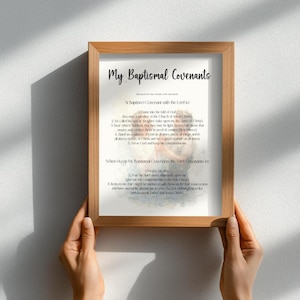 May include: A framed print with the text "My Baptismal Covenants" in a handwritten style. The print includes a list of covenants and is held by a person. The frame is made of wood.