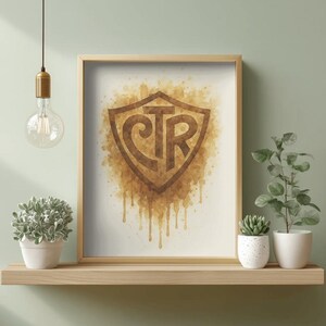 May include: A framed print featuring a brown shield design with the letters "CTR" in a stylized font. The artwork has a watercolor effect with dripping paint. The print is displayed on a wooden shelf with potted plants.