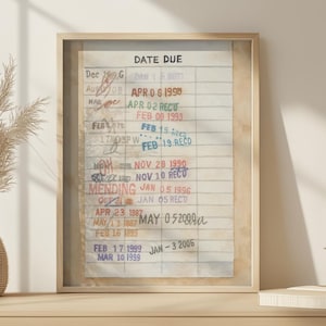 May include: Framed vintage library card with the words "DATE DUE" at the top. The card has handwritten and stamped entries with dates from the late 1800s to the early 2000s. The frame is a light wood color.