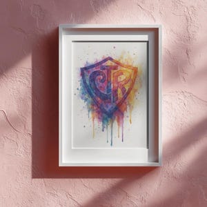 May include: A framed watercolor print featuring a shield design with the letters "CTR" in a vibrant, multi-colored palette. The artwork showcases a blend of blues, purples, yellows, and oranges, with paint drips adding a dynamic effect. The white frame contrasts the colorful art.