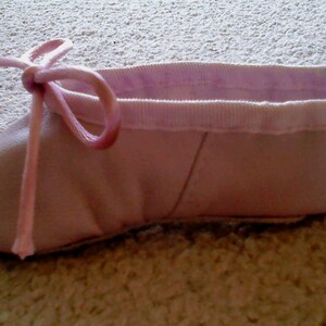 May include: A pink ballet slipper with a pink ribbon tied around the ankle.