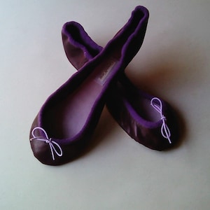 May include: A pair of purple ballet flats with a small bow on the toe.