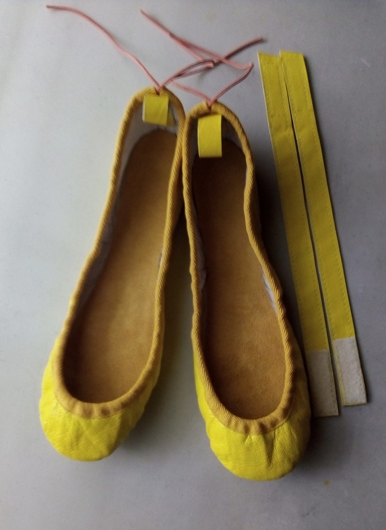 May include: Two yellow fabric ballet flats with a pair of yellow fabric ties.