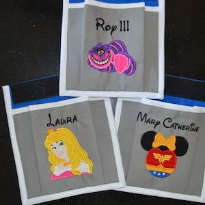 May include: Three gray fabric bags with white trim and blue accents. Each bag has a different embroidered design and name. The first bag has a purple Cheshire Cat design and the name "Roy III". The second bag has a pink and yellow princess design and the name "Laura". The third bag has a black and red Minnie Mouse design and the name "Mary Catherine".