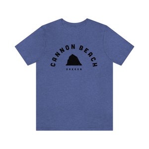 Peut inclure: Un t-shirt bleu avec un motif noir d'une montagne et le texte "Cannon Beach Oregon".