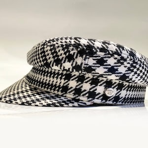 May include: A black and white checkered newsboy cap with a silver button on the side.