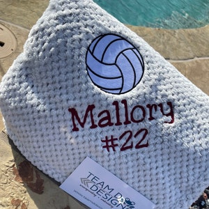May include: A white, fuzzy blanket with a white volleyball and the name "Mallory #22" embroidered in maroon.